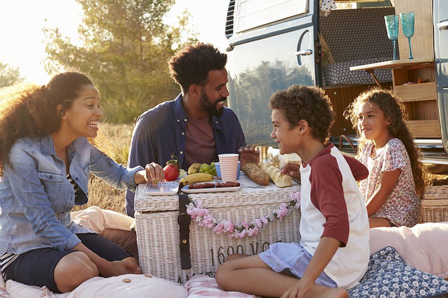 Personal Insurance - Family on Vacation Having a Picnic Outside at Dusk Beside their Camper
